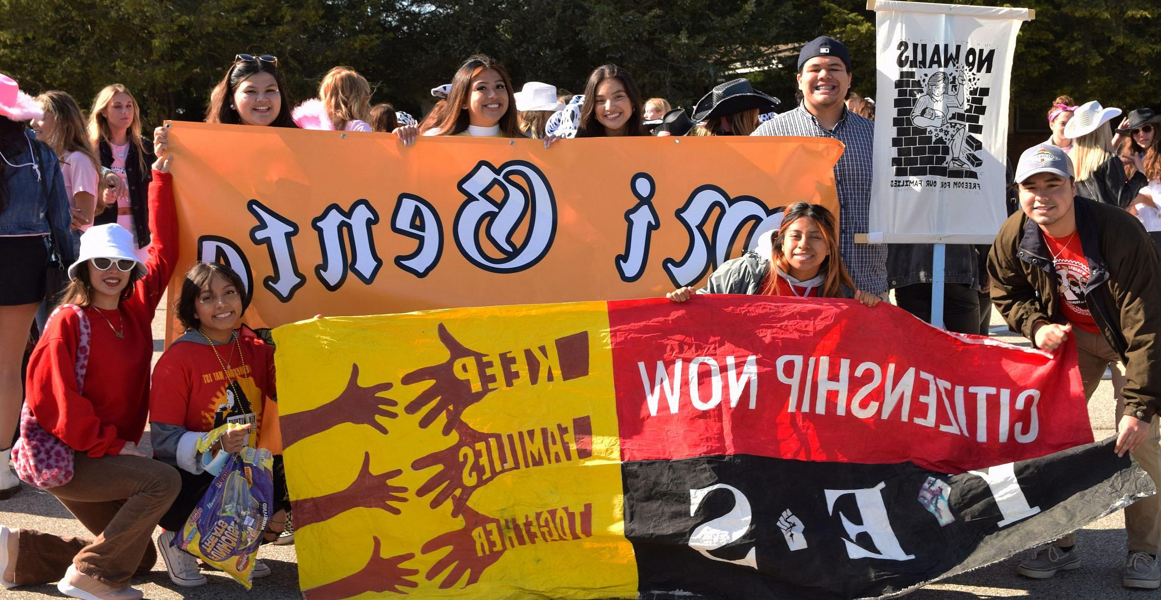 Students in the student org Mi Gente carry their banners and signs at the 2021 Homecoming Parade. 